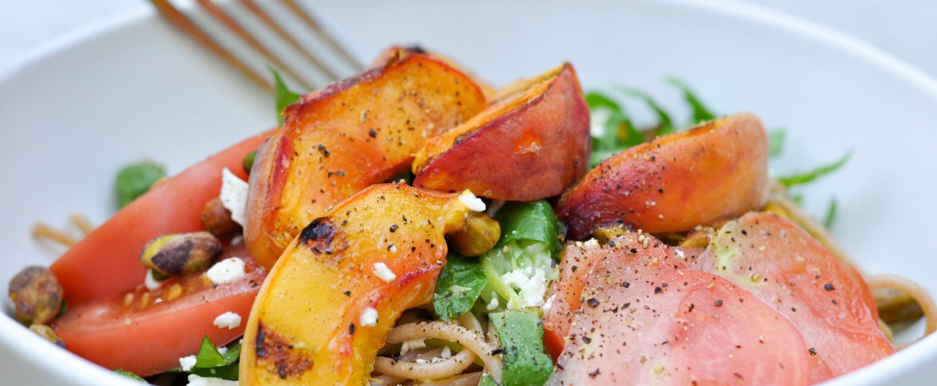 Bowl of zucchini pasta with peaches, tomatoes, feta, and sorel